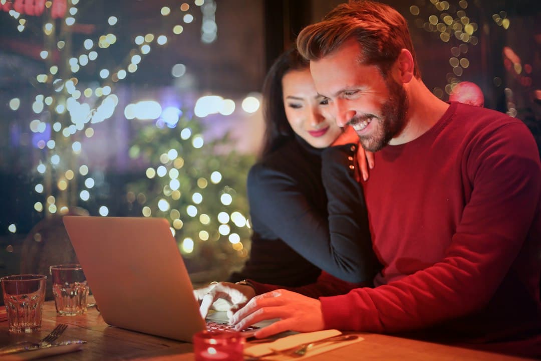 A couple sitting together at a table, using a laptop to search for couples therapy options online.